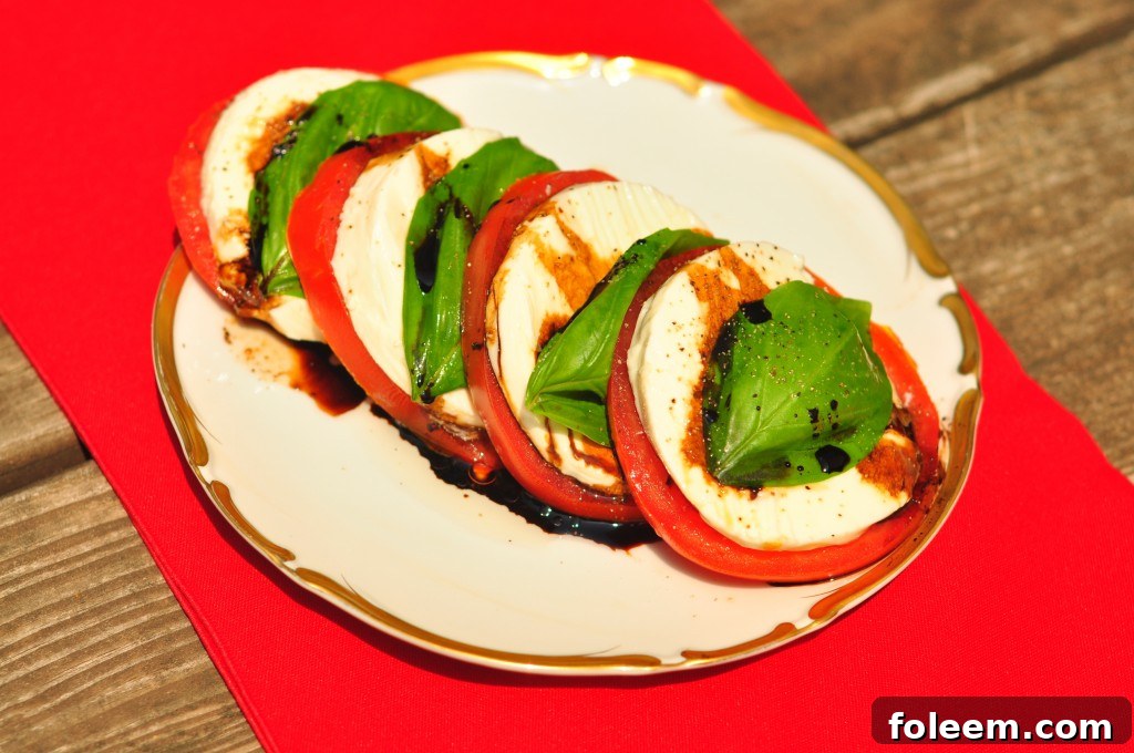 Close-up of a meticulously arranged Caprese Salad showcasing sliced tomatoes, fresh mozzarella, and basil leaves ready for balsamic drizzle.