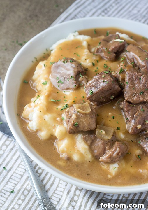 Slow Cooker Beef Tips and Gravy, a simple yet elegant meal, served over noodles, perfect for dinner guests or a cozy family supper.