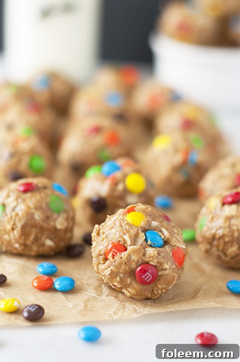 Close-up of healthy No-Bake Monster Cookie Dough Energy Bites, featuring chocolate chips and M&Ms.