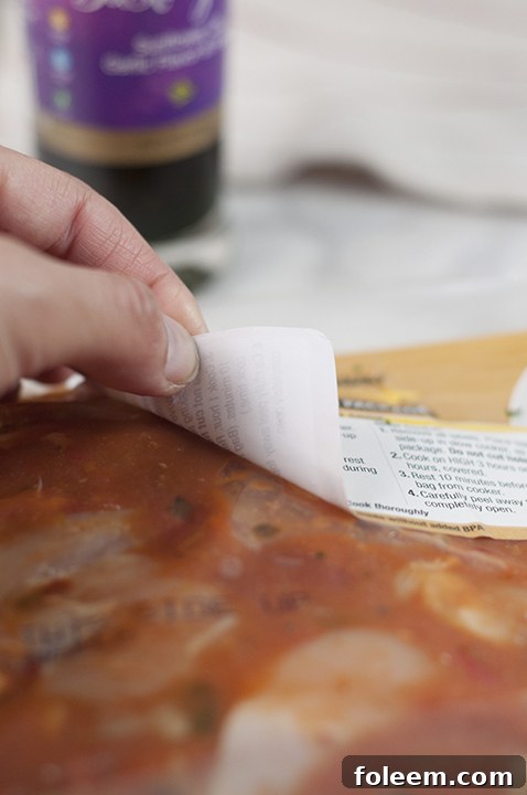 Peeling off the label from the vacuum-sealed plastic package of Wegmans Chicken Cacciatore, ready for cooking.