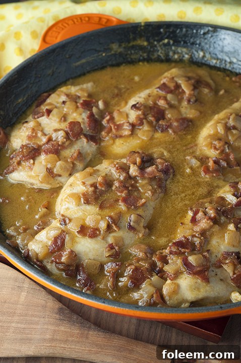 Maple Mustard Bacon Chicken Skillet with perfectly cooked chicken, crispy bacon bits, and a rich, creamy sauce, served in a cast iron skillet on a rustic wooden board.