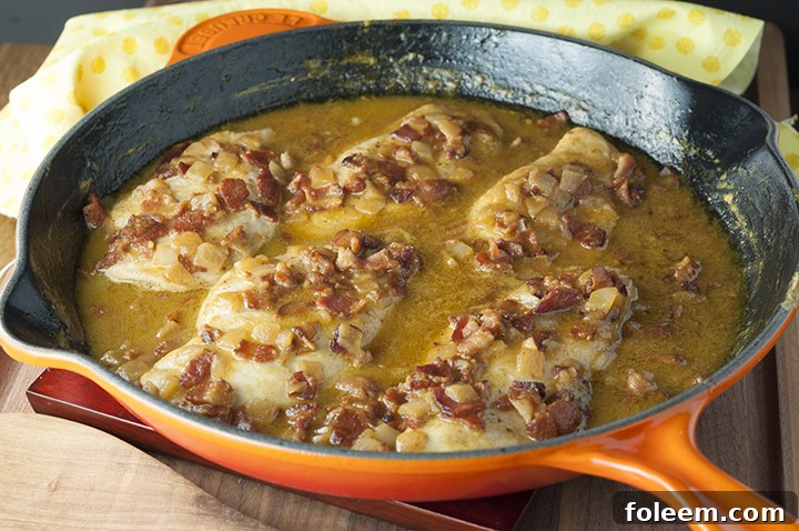 Close-up shot of Maple Mustard Bacon Chicken Skillet, highlighting the tender chicken pieces, crispy bacon, and the rich, golden-brown sauce simmering in the skillet.