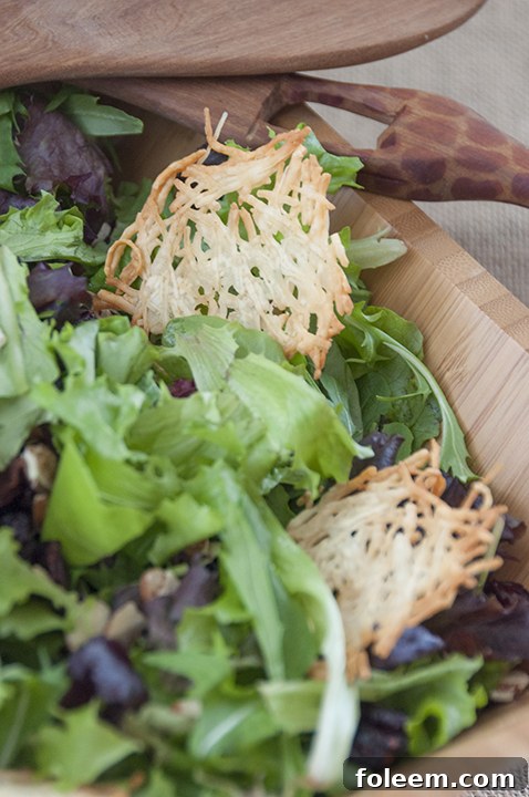 Close-up of baked Parmesan crisps cooling on a rack, showing their delicate, golden-brown edges and crispy texture.