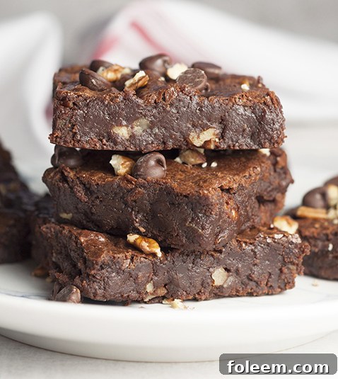 A stack of perfectly cut, rich chocolate brownies with visible pecan pieces, ready for serving.