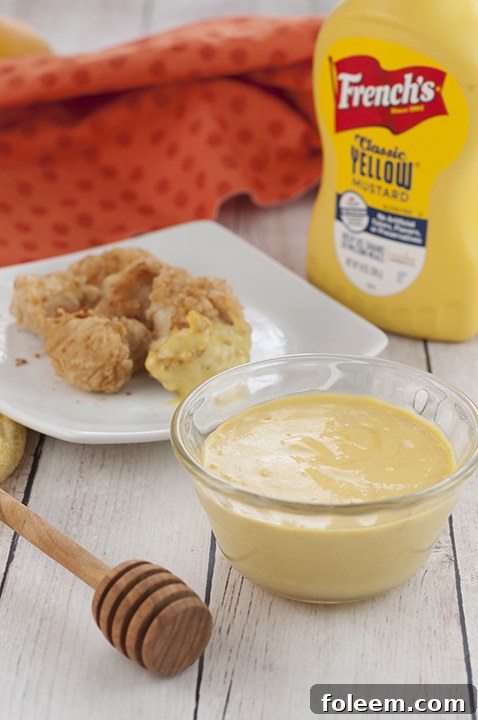 Extremely easy smooth and creamy 4 ingredient Honey Mustard Dipping Sauce recipe you can dip soft pretzels or French fries in, spread on grilled chicken, potatoes, mini meatballs, and more!