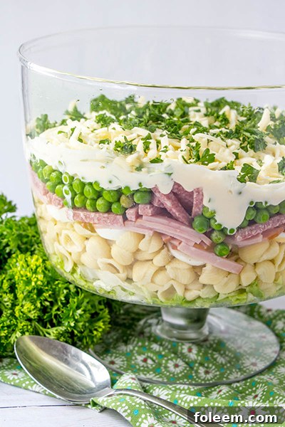 Colorful eight layer salad in a glass bowl, ready for a party.