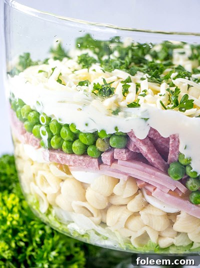 Close-up of a vibrant, fresh layered salad with ham and peas.