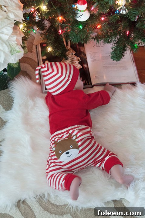 Baby Eliza reading a book under the Christmas tree.