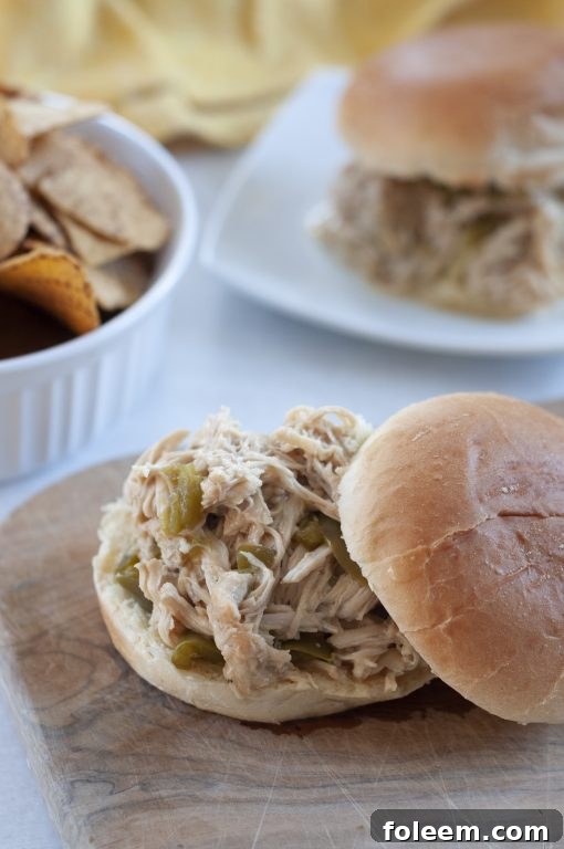 A serving of Slow Cooker Pulled Cheesesteak Chicken on a toasted bun, garnished with fresh parsley, ready to be enjoyed.