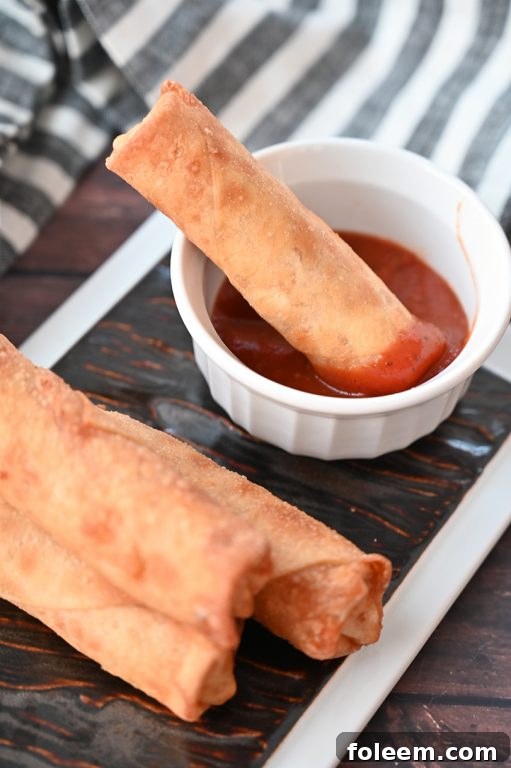 Baked pepperoni pizza rolls arranged neatly on a serving board with a dipping bowl