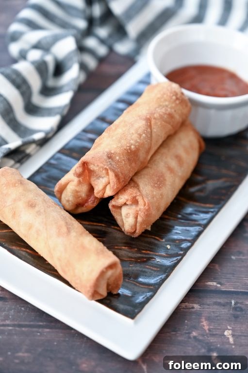 A close-up of a stack of baked pepperoni pizza rolls, highlighting their golden crispness