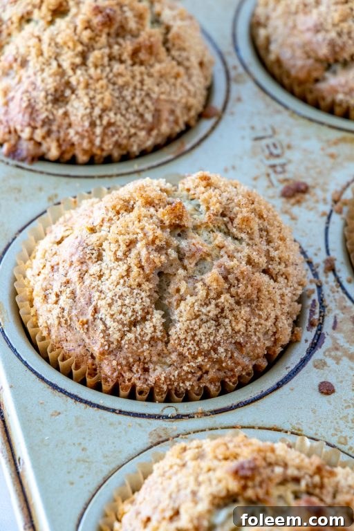 A beautifully arranged stack of three banana crumb muffins on a rustic board, inviting a taste.