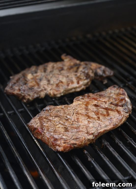 Ribeye or Delmonico steaks sizzling on a Weber grill, capturing the essence of outdoor cooking and perfect searing.