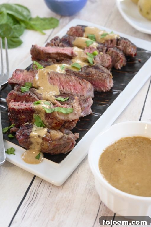 Beautifully plated grilled ribeye steak with a generous drizzle of onion blue cheese sauce, highlighting its simple elegance for a summer meal.