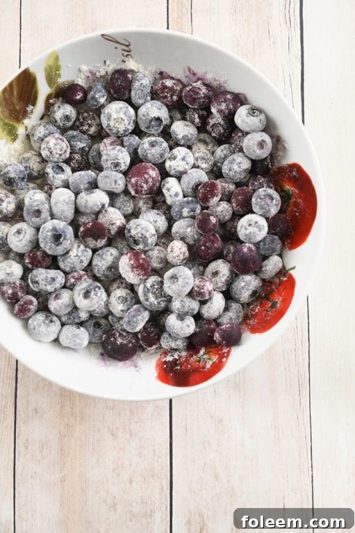 Close-up shot of a slice of moist Blueberry Banana Bread, showcasing baked blueberries and a golden-brown crust. Ideal for a sweet snack.