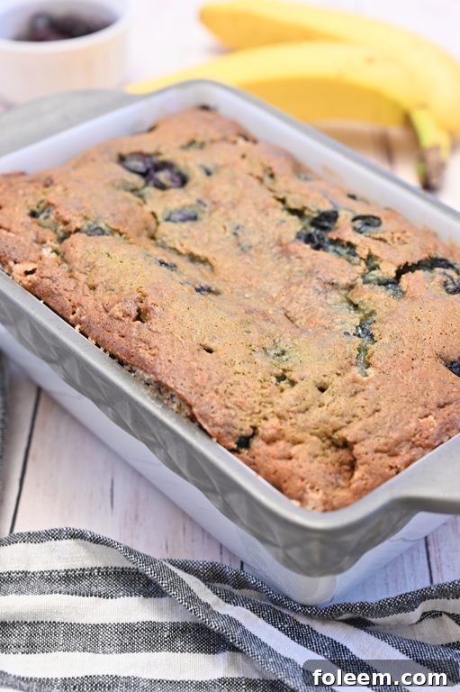 Freshly baked Blueberry Banana Bread cooling on a wire rack, with a view of the golden crust and soft interior. A perfect treat.