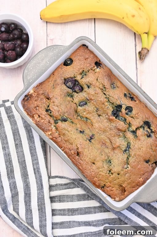 Delicious slice of moist Blueberry Banana Bread, showing the fluffy texture and distribution of blueberries, ready to be enjoyed.