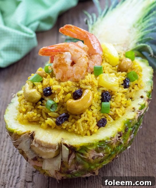 Delicious Pineapple Shrimp Fried Rice in a half pineapple shell, garnished with fresh cilantro and lime wedges, ready to be served.