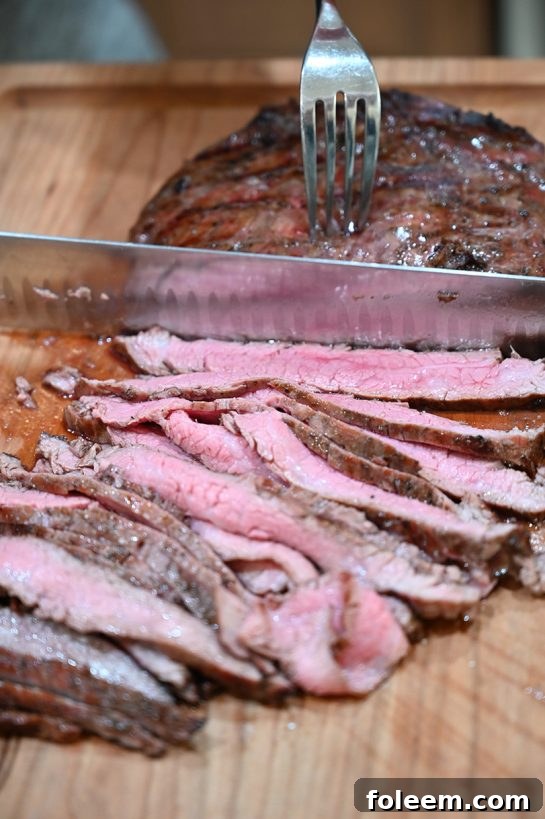 Slicing perfectly grilled flank steak against the grain for maximum tenderness.