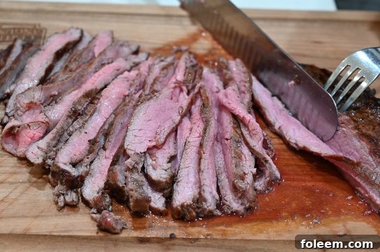 Slicing juicy, medium-rare grilled flank steak against the grain, ready for tacos.