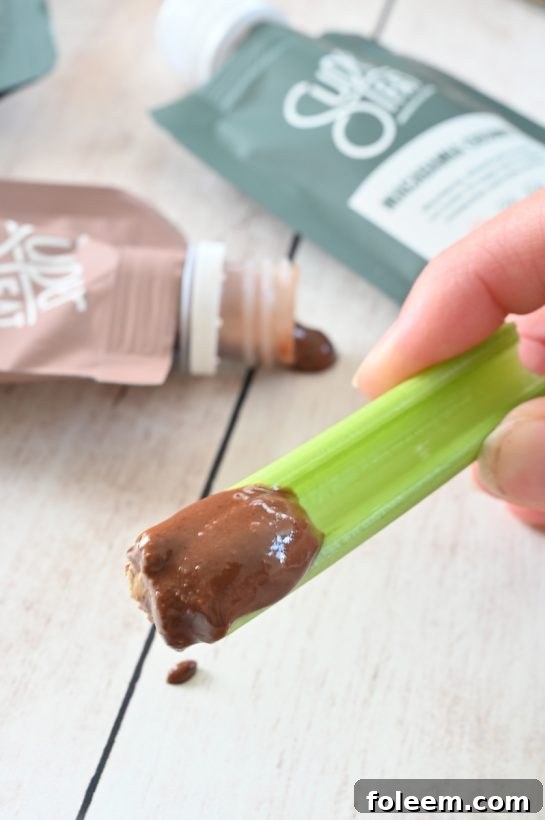 A gluten-free, vegan Mason Jar Pretzel, Celery, Almond Butter Snack with SuperFat nut butter, providing a healthy, protein-rich energy boost at any time of day.