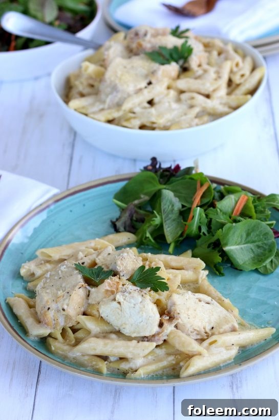 Chicken Alfredo plated with a side salad.