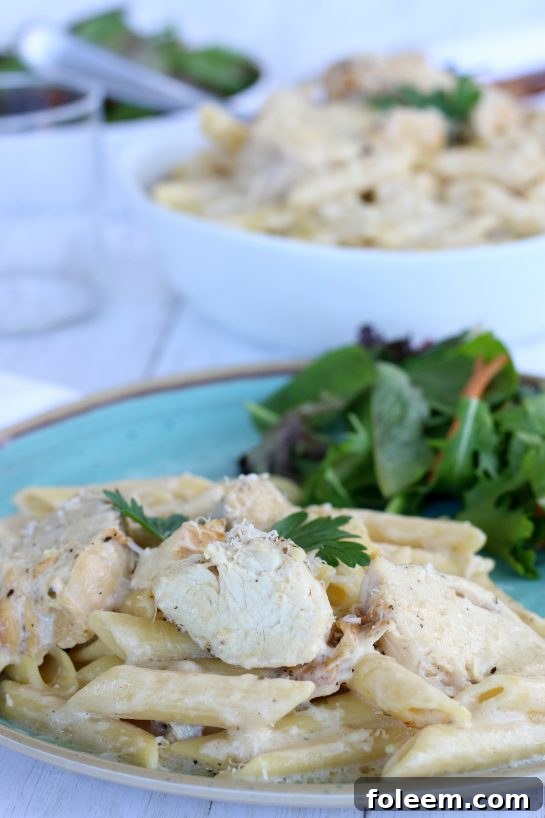 Chicken Alfredo plated with a side salad for an easy crock pot pasta dinner recipe.