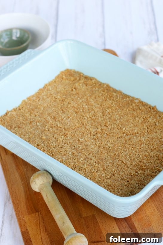 A light blue coloered baking dish with the graham cracker crust for a cheesecake.