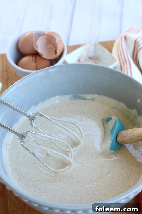 Eggs and cream cheese, along with ground cinnamon, ginger and cloves blended together to make a batter for cheesecake bars.