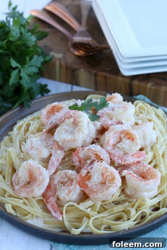 Beautifully plated shrimp with garlic sauce layered over pasta for an easy dinner recipe.