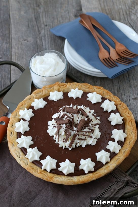Finished homemade chocolate pie topped with perfectly fluffy whipped cream, a slice elegantly removed, ready to be eaten. A true dessert dream come true.