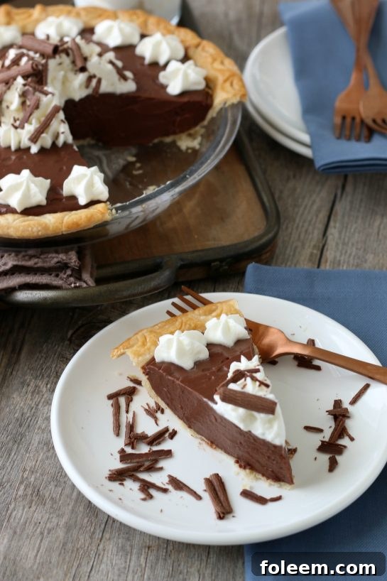 A beautifully presented slice of homemade chocolate pie, perfectly cut and served on a plate, adorned with whipped cream, inviting immediate enjoyment.
