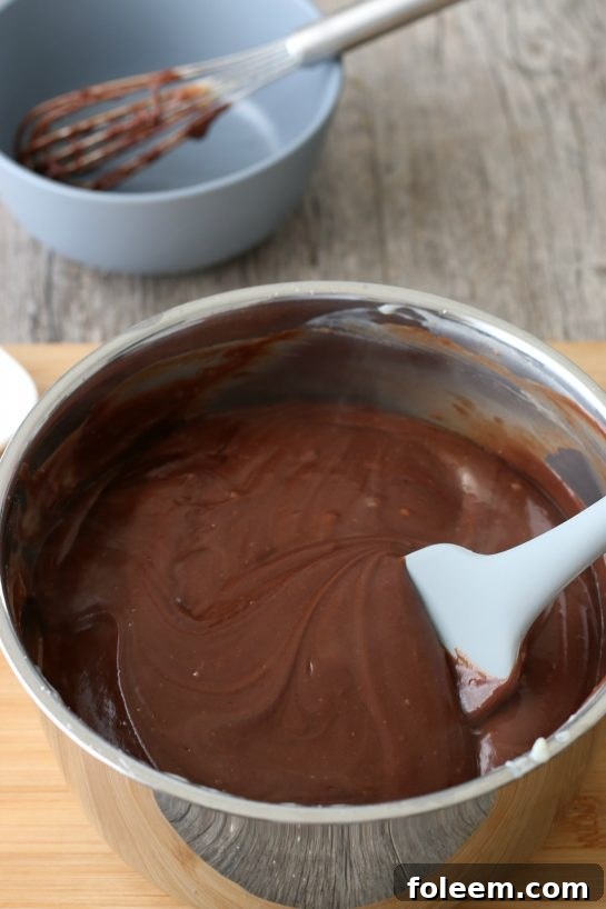 A visual delight: the rich, creamy homemade chocolate pie filling is captured in its final stages, looking incredibly luscious and almost ready to be poured.
