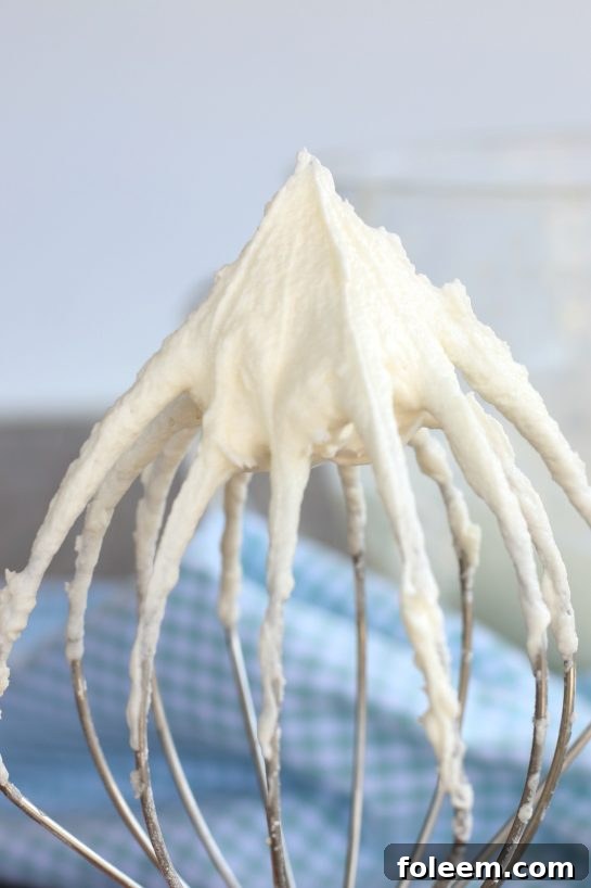 The best buttercream frosting recipe is in finished and being shown stuck to the whisk!