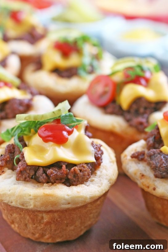 A vibrant display of finished cheeseburger biscuit bites, beautifully topped with fresh shredded lettuce and crisp pickle slices, ready to be enjoyed. A perfect appetizer or family dinner!