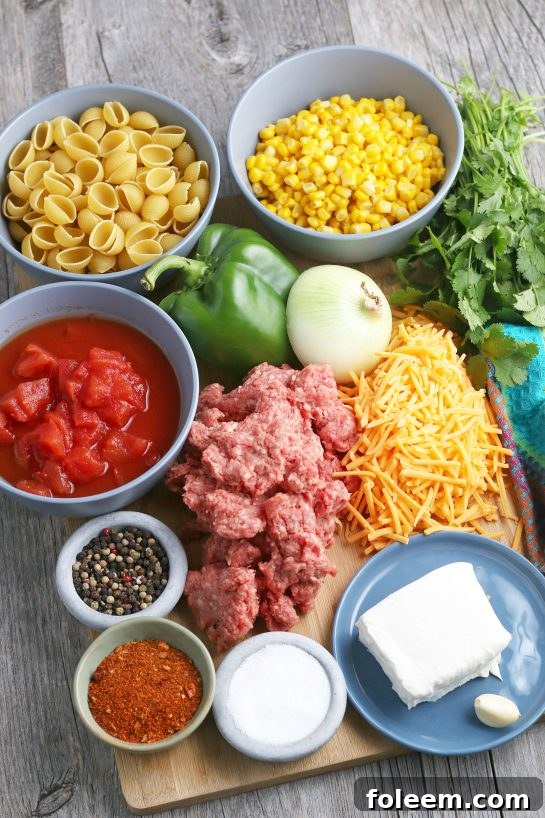 A collection of fresh ingredients laid out on a kitchen counter, ready to be used for the taco pasta recipe, including ground beef, bell peppers, onions, and spices.