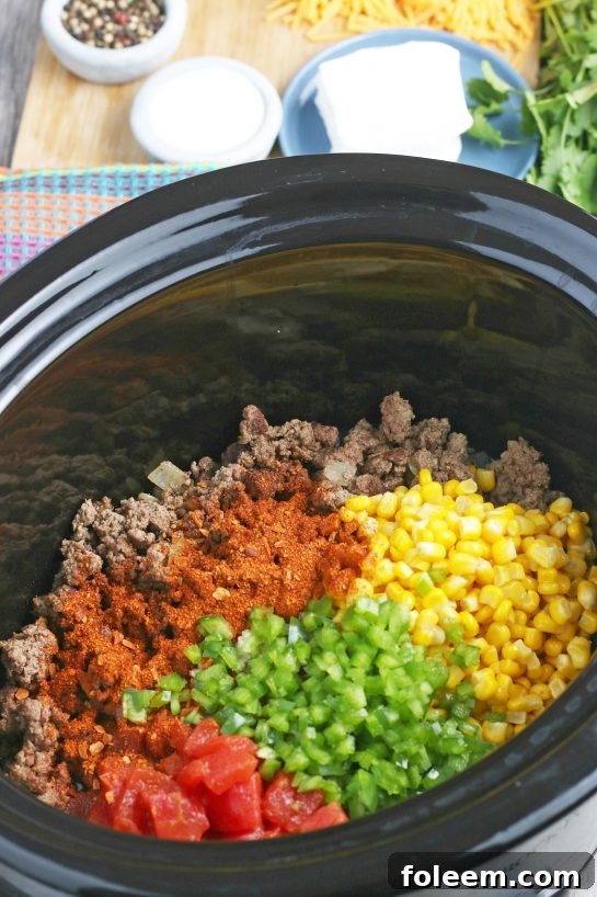Layering ingredients into the slow cooker for the Mexican pasta salad, showing colorful vegetables and seasonings being added.