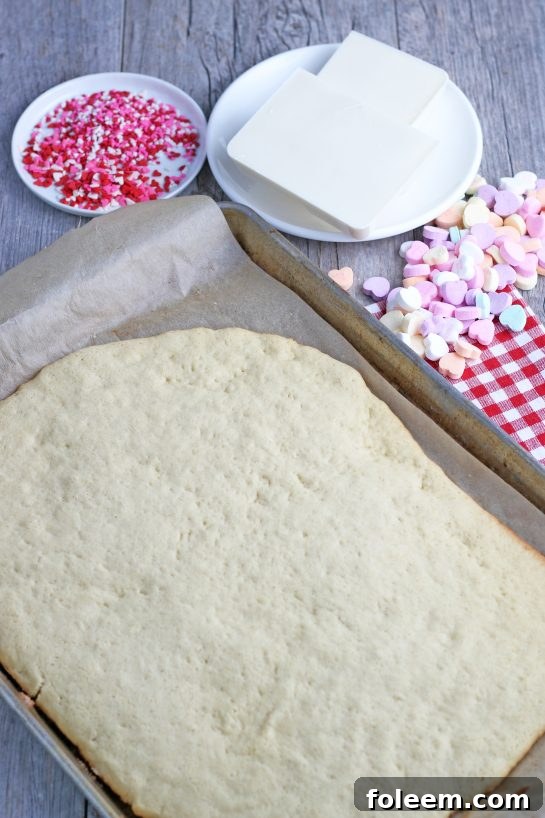 The baked sugar cookie sheet is now perfectly golden and ready to receive its festive toppings, including a luscious icing and a cascade of colorful sprinkles.