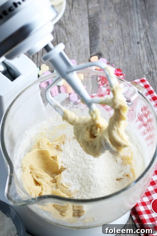 A close-up view inside the stand mixer, showing the initial stages of mixing the wet ingredients for the sugar cookie dough, which forms the delicious bark base.