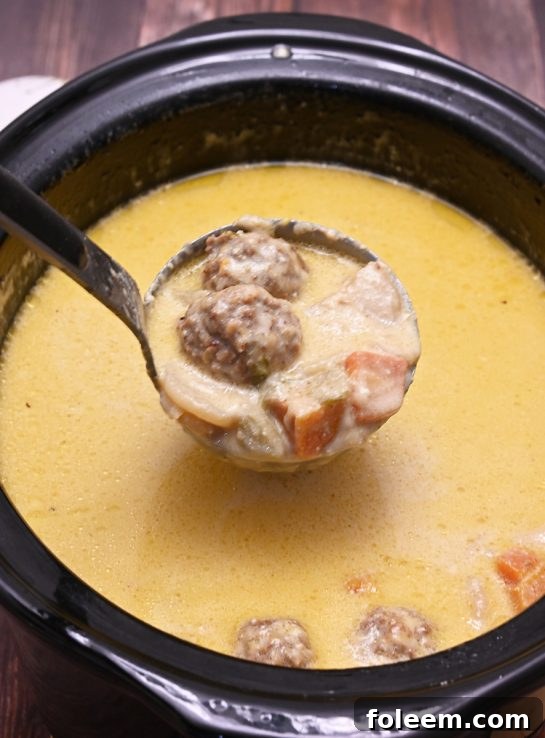 Closeup of creamy Slow Cooker Cheesy Meatball Soup in a bowl, with bread