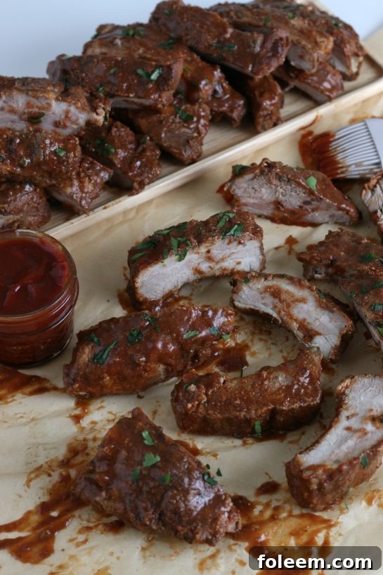 This image shows some of the finished crock pot ribs stacked on a platter and others in the front ready to be grabbed for a yummy meal!