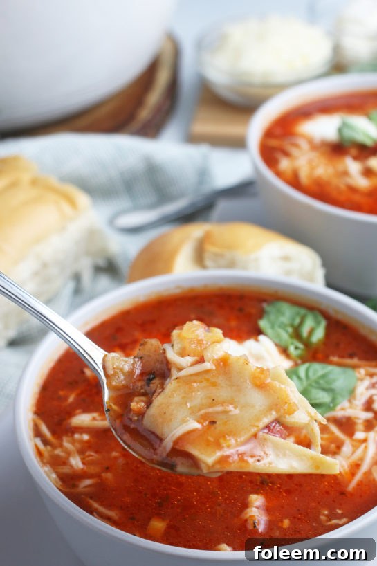 This view of the finished cheesy lasagna soup has a spoonful lifted up so we can see all the great texture and flavors ready to be eaten.