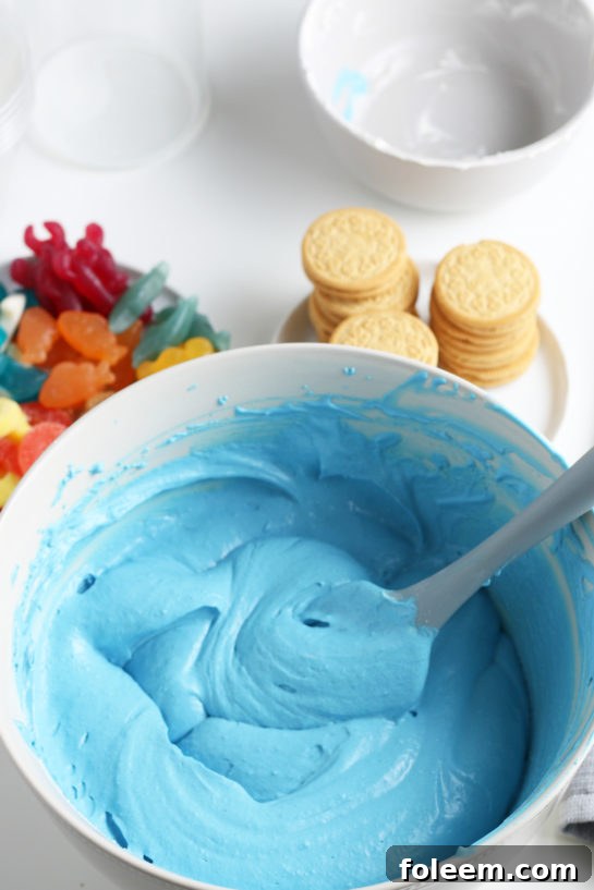 Mixing together the blue jello and whipped topping to make this beach sand pudding cups recipe