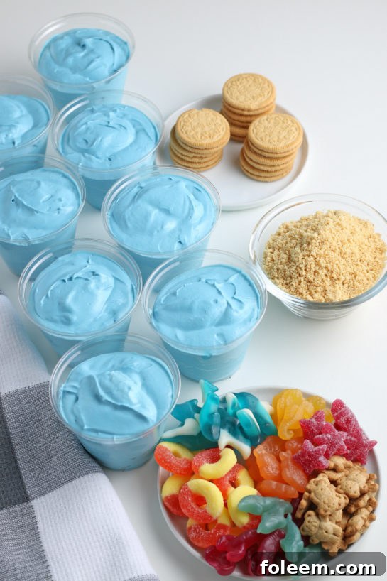 Pouring the blue jello mix into the plastic cups for the beach sand pudding cups recipe