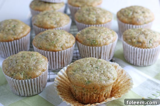 Horizontal close-up of a batch of perfectly baked Zucchini Muffins, showcasing their golden exterior and inviting texture, ready to be enjoyed.