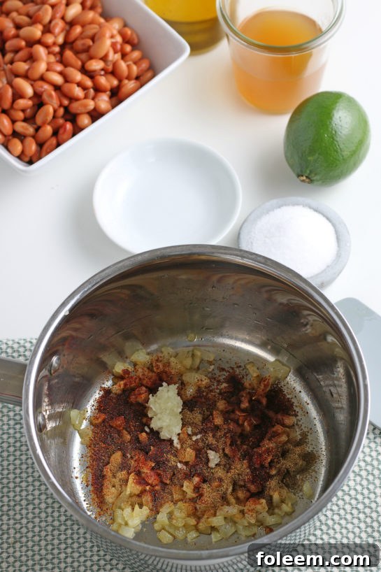 Adding aromatic spices like cumin and chili powder to the cooked onions and garlic.