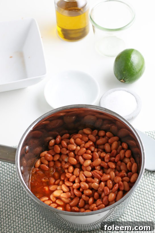 Pinto beans and stock simmering in a pot, absorbing the rich flavors.