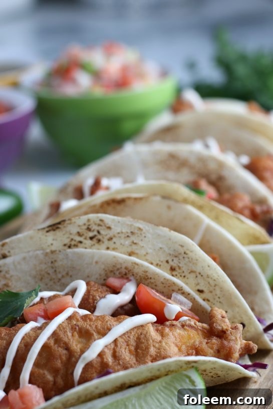 Close-up shot of two beer-battered Baja Fish Tacos, showing the crispy fish and fresh ingredients