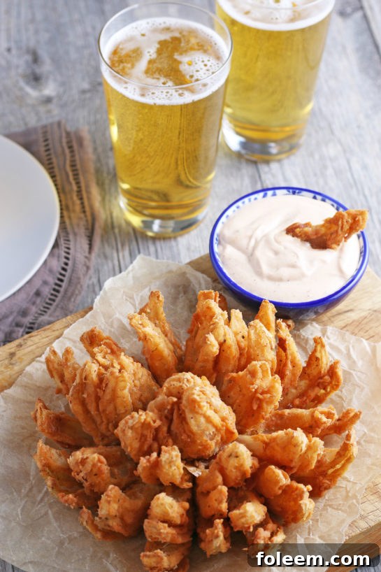 Golden Fried Blooming Onion served with a creamy homemade dipping sauce, presented beautifully as the perfect game day snack.