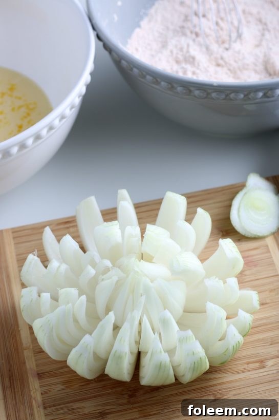 The process of slicing an onion to create a 'bloom' effect, showcasing how the petals are separated for frying.